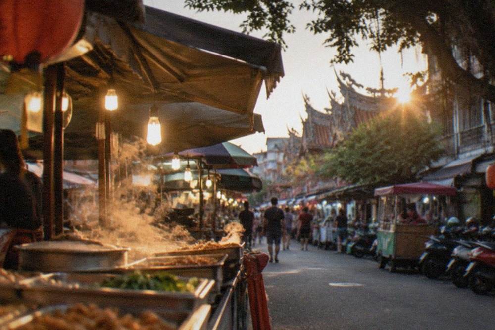 A busy Tainan night market stall at dusk with steam rising from cooking trays