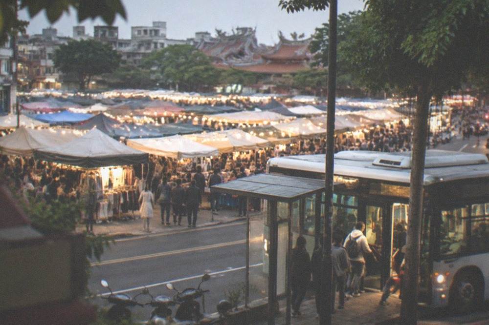 A Taiwanese city bus at a lit stop in the evening, with passengers boarding through the front door