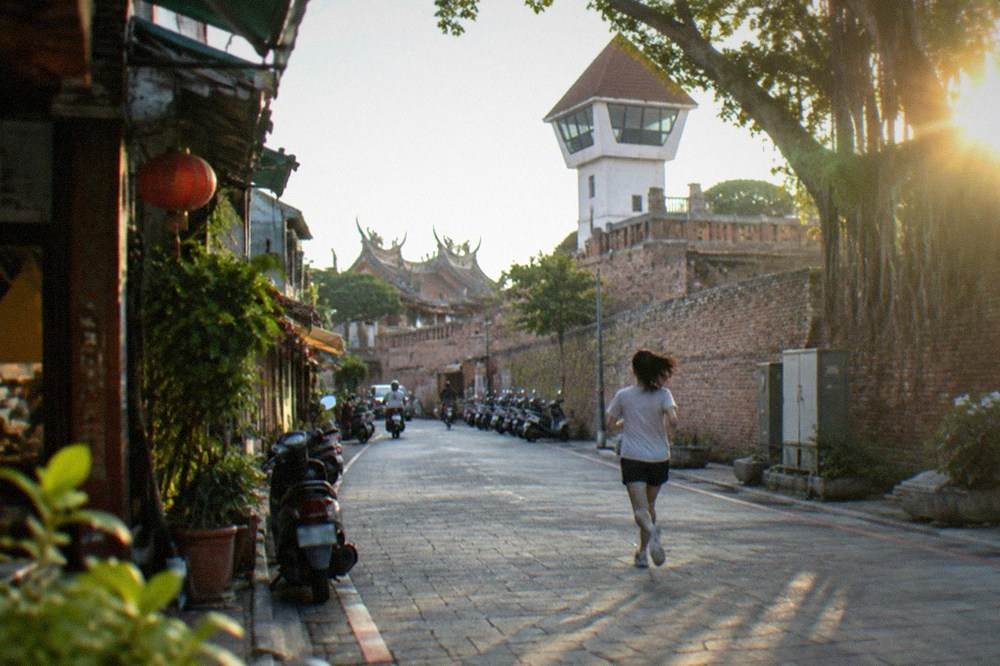 Old brick rampart walls and a white lookout tower at a historic fort in Anping