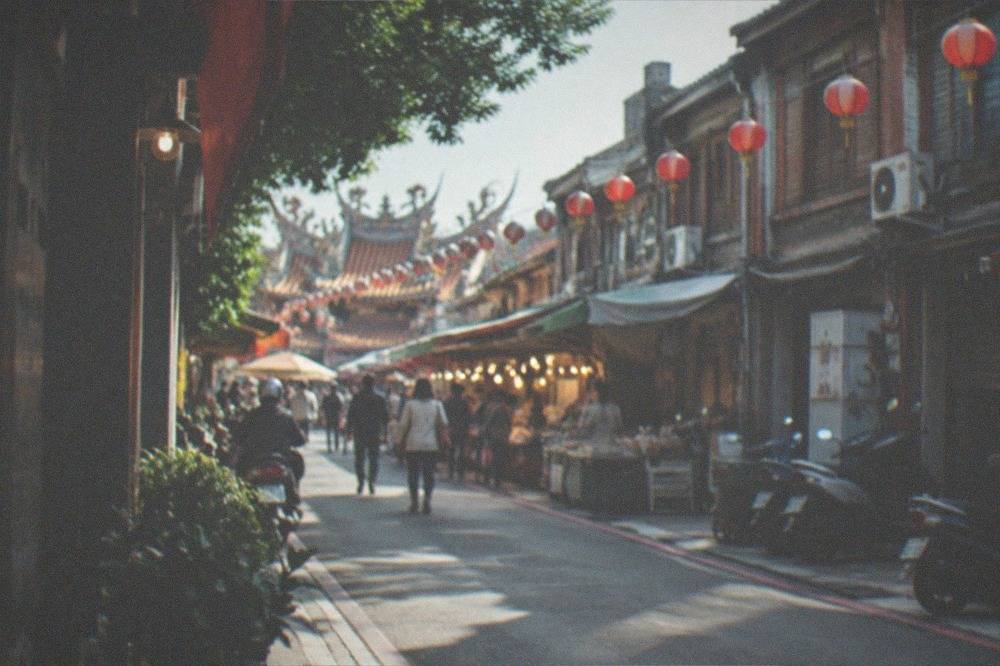 Crowded night market aisles lit by rows of warm stall lights at dusk