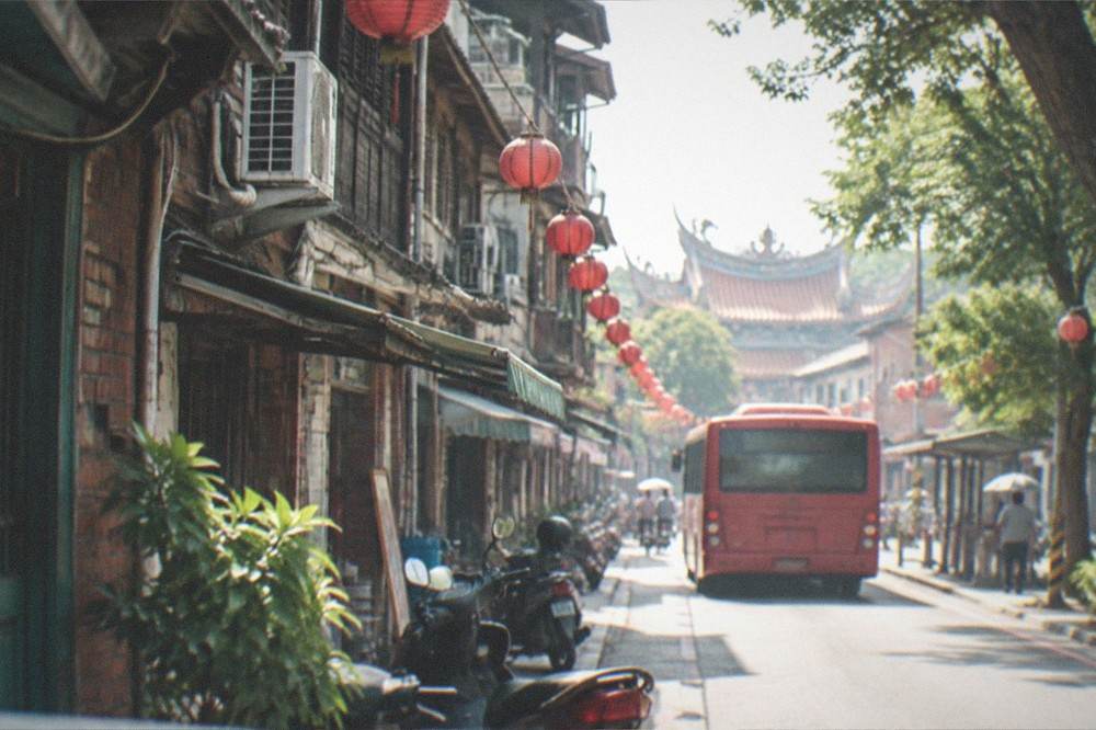 A red city bus at a stop on a sunny street in Tainan