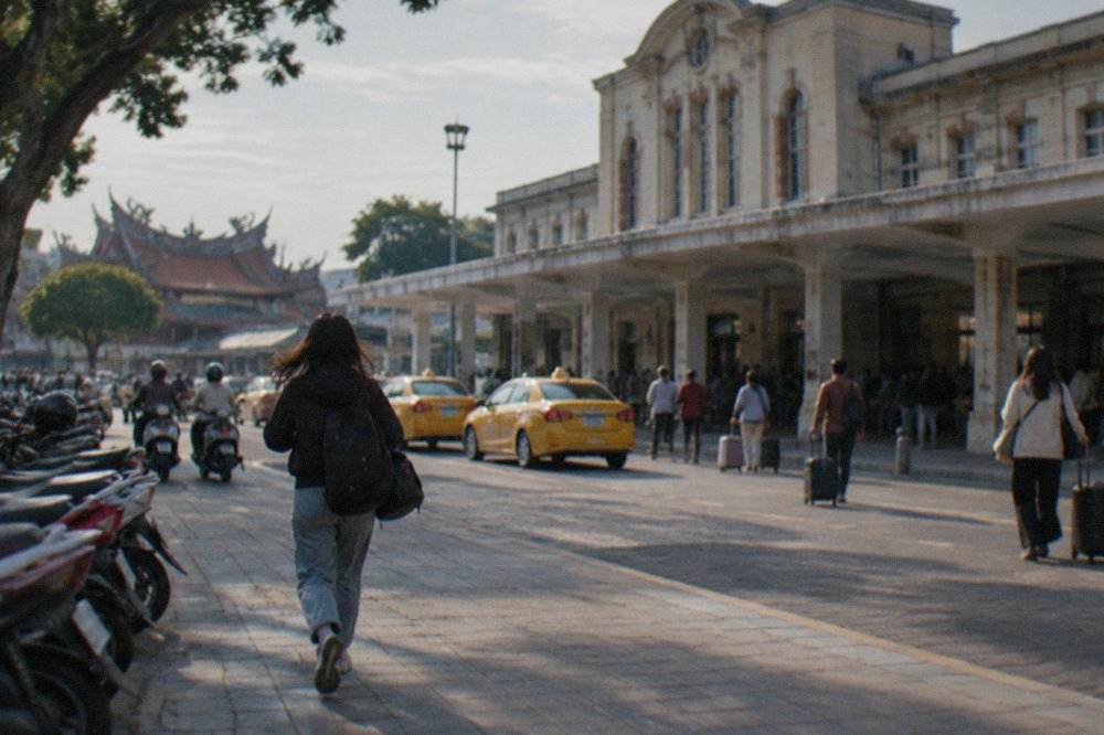 The historic facade of Tainan Railway Station with its front plaza and waiting travelers