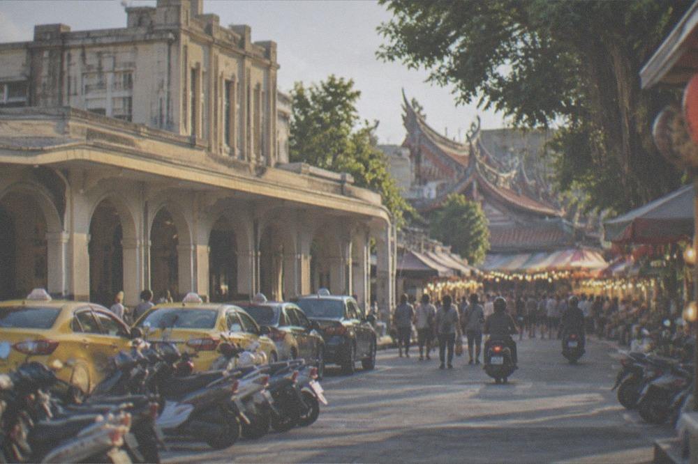 Crowded night market aisles lit by strings of stall lights in the evening