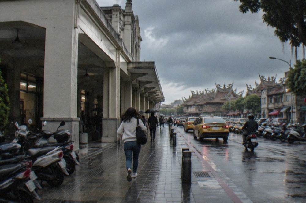 Rain clouds over a Tainan street with temple rooftops in the distance