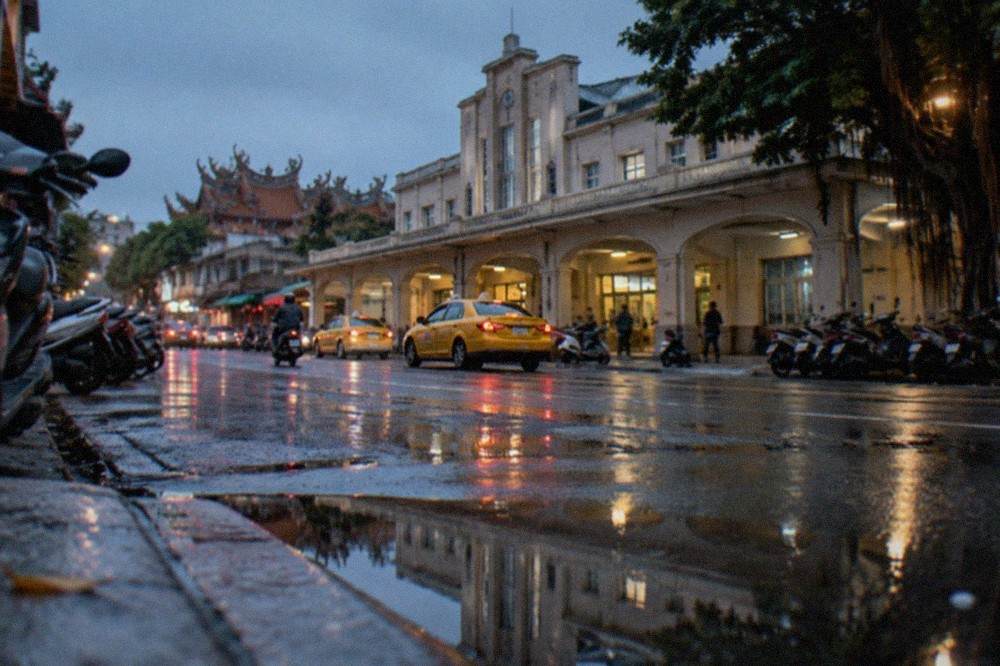 A wet street in Tainan with reflections in puddles and closed shopfronts