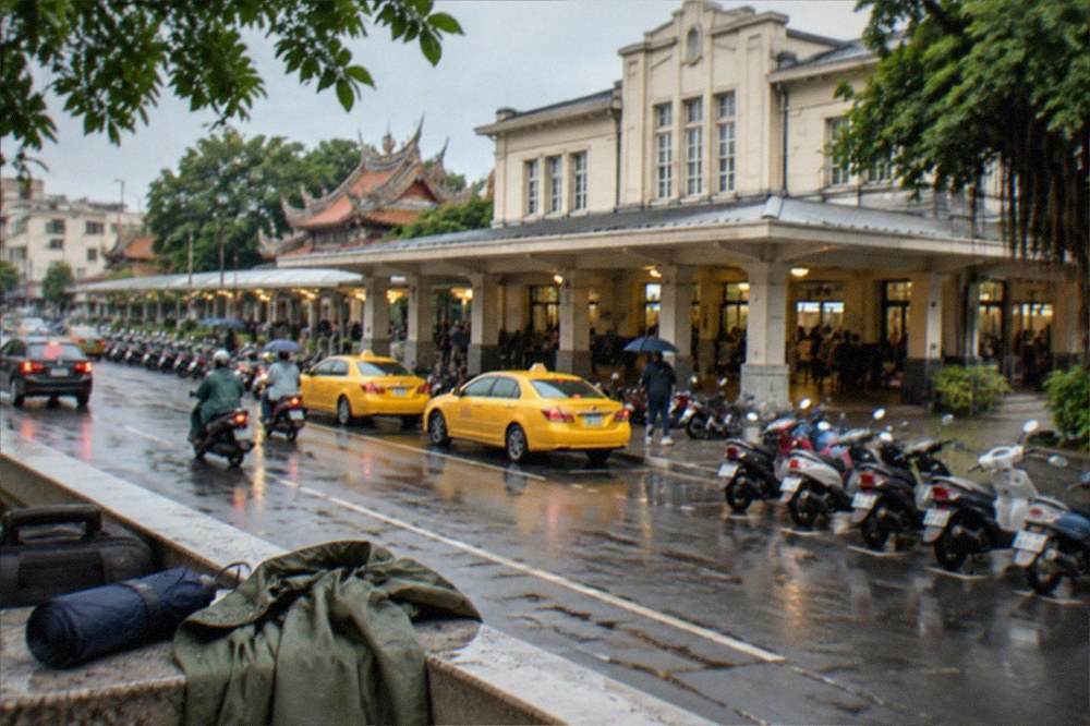 A compact umbrella and light rain jacket on a table beside a travel map