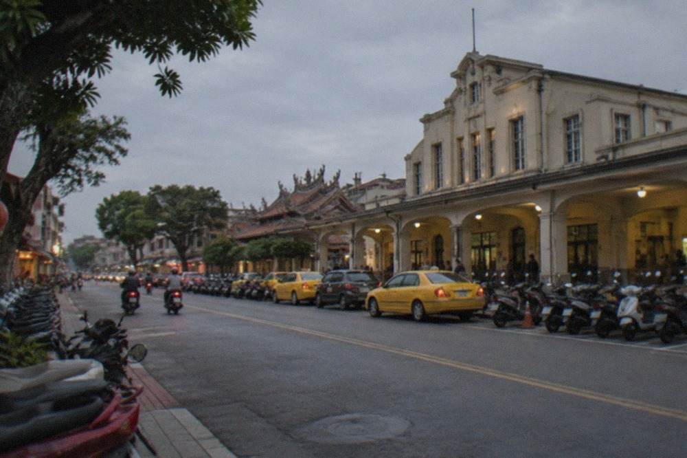 A quiet Tainan street at dusk with scooters parked along the sidewalk