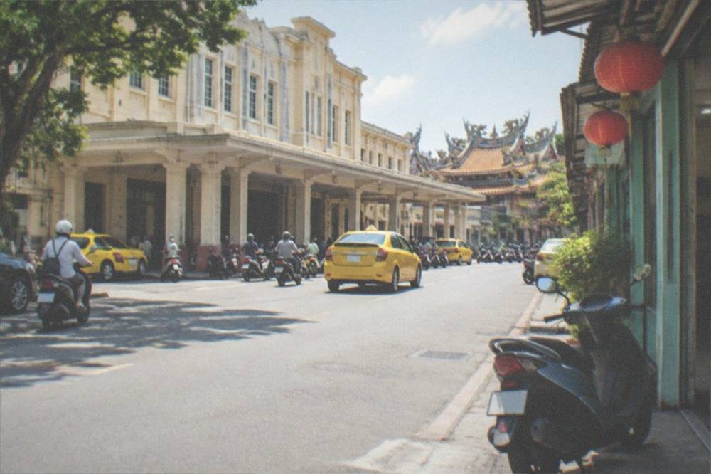 A scooter parked outside a small rental shop front in a Taiwanese street