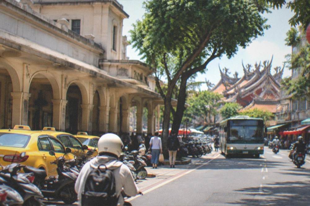 A Tainan street with pedestrians and a city bus in the evening