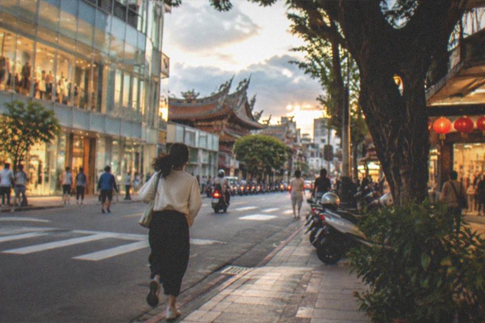 An evening street in Tainan with lit shopfronts and people walking