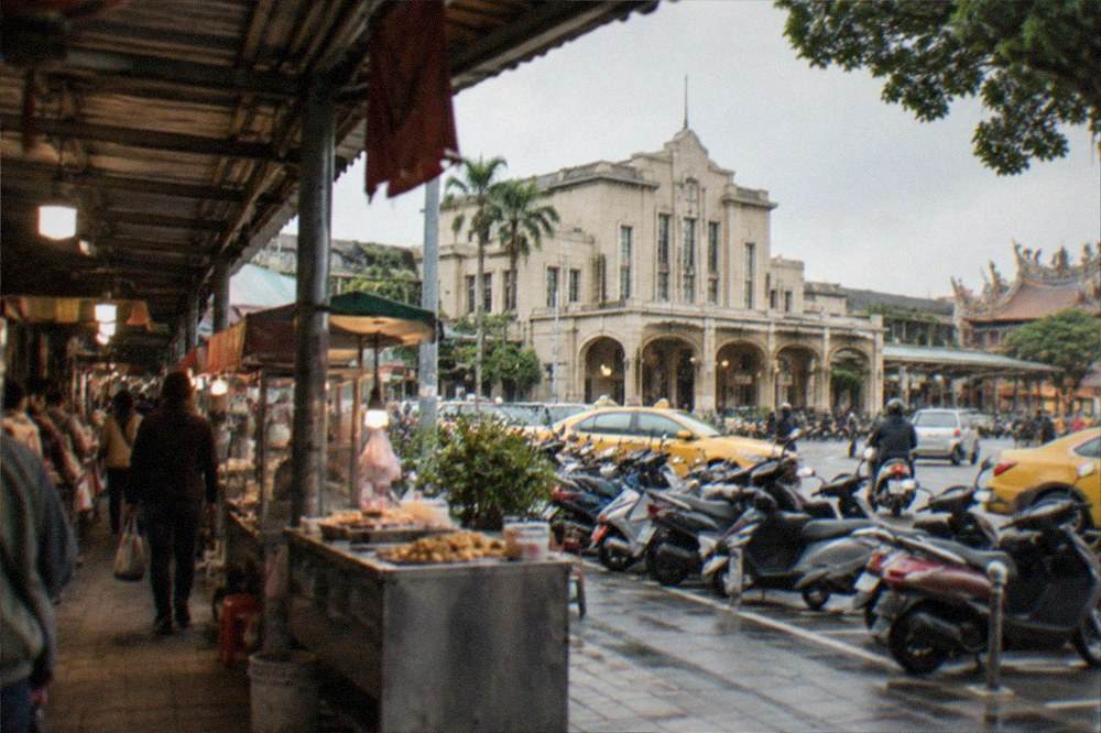 A covered market walkway with food stalls and shoppers under a roof