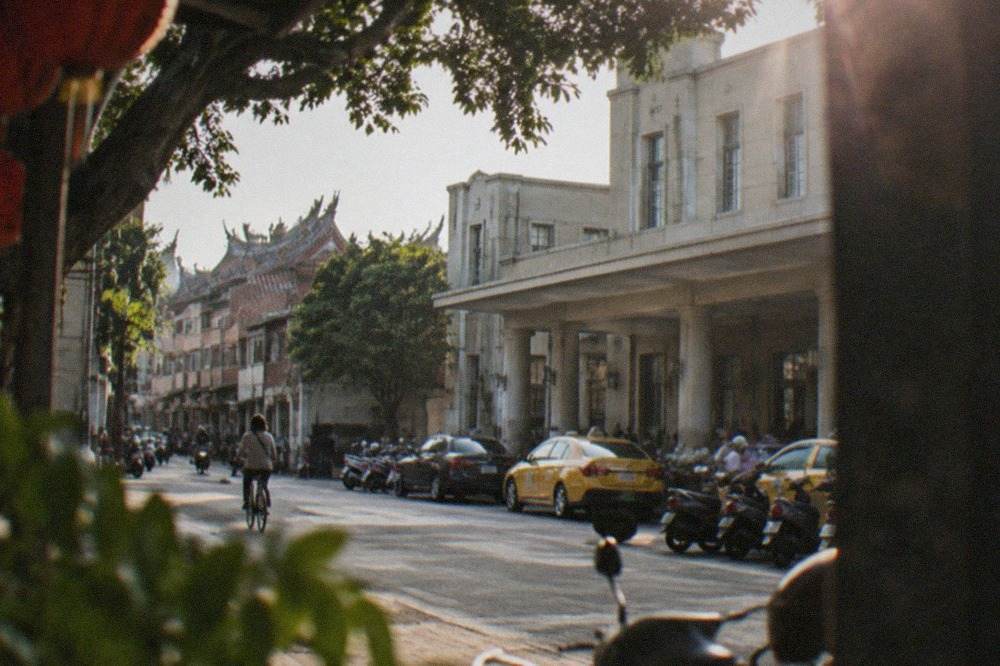 A quiet old street in Tainan with low brick buildings and a lone cyclist passing by