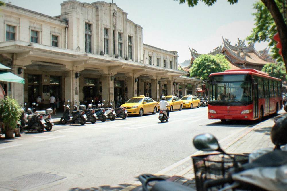 A red Tainan city bus at a curb on a sunny street