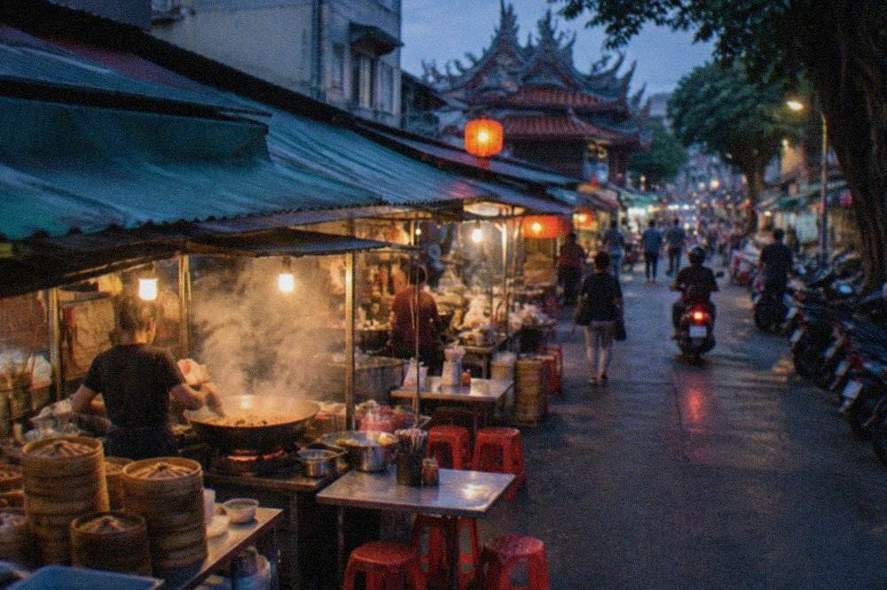 A busy Tainan street food stall at night with steam rising from a cooking wok