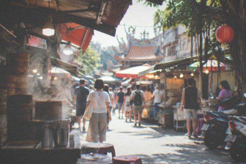 Crowds walking between food stalls under lights at a large Tainan night market