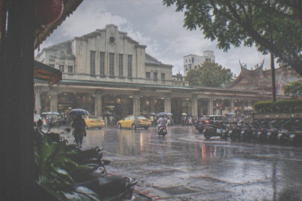 Heavy rain falling on an empty street in a Taiwanese city with umbrellas