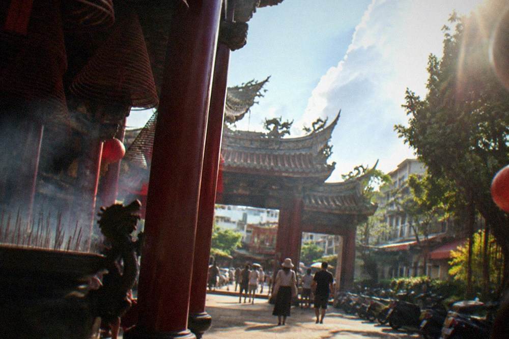 Visitors in modest summer clothing walking through a temple gate in Tainan