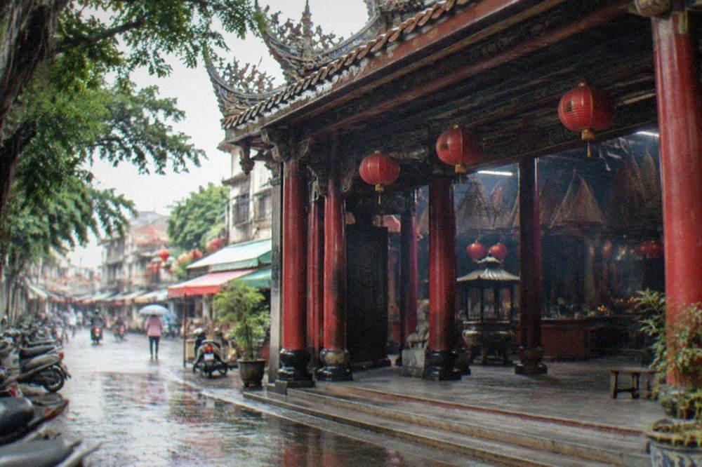The entrance gate of a traditional Taiwanese temple with red pillars and hanging lanterns
