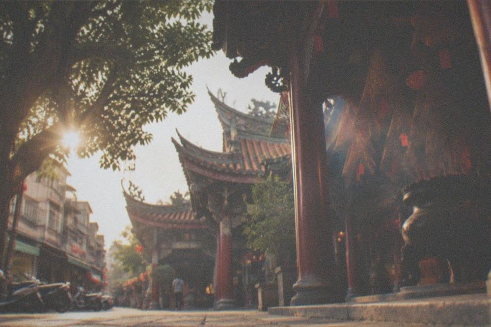 A quiet temple courtyard in late afternoon light with stone paving and old trees