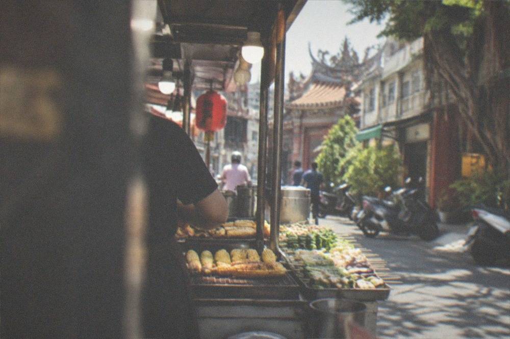 A night market stall with grilled corn and vegetable skewers under lights