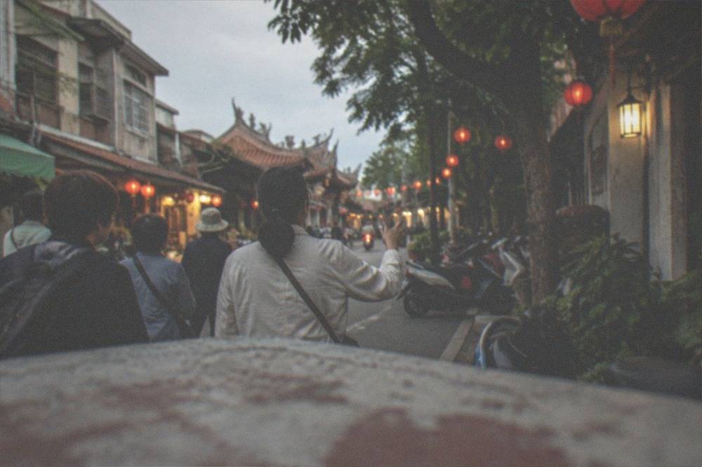 A guide leading a small group of visitors along a lantern-lit street in the evening