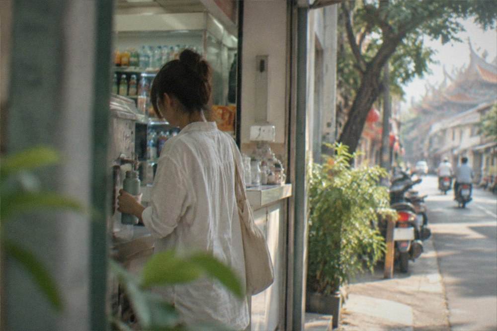A visitor refilling a water bottle at a convenience store counter in Taiwan