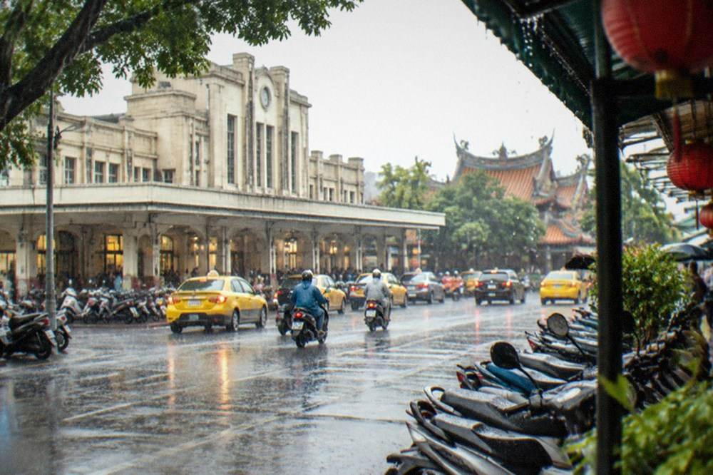 Heavy rain falling on a Tainan street with scooters parked under awnings