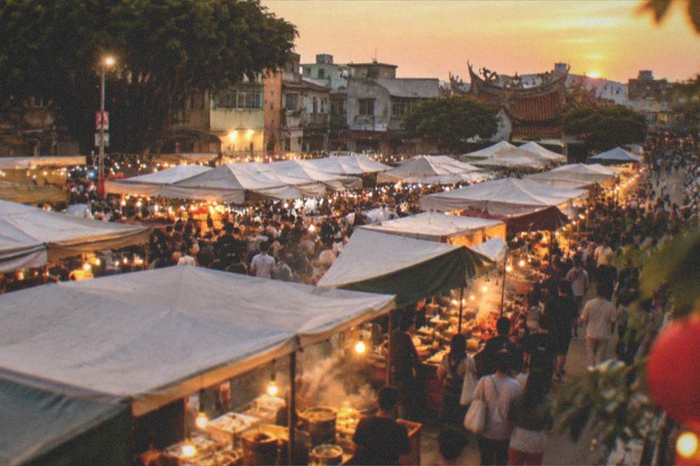 Steam rising from food stalls at a busy Tainan night market after dark