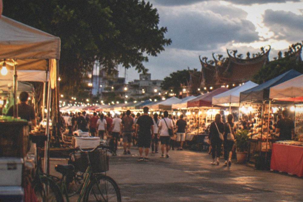 Night market stalls glowing under lights with a bicycle parked in the foreground