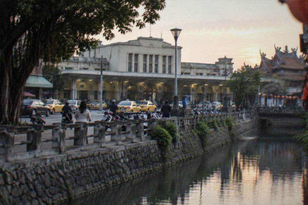 A canal in an old Taiwanese city at dusk with stone banks and lanterns