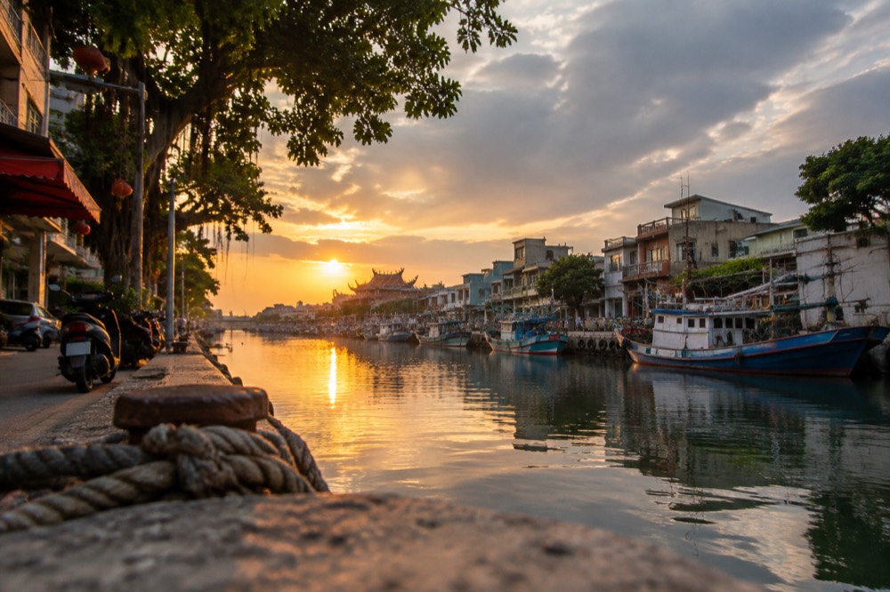 Sunset light over the Anping canal with boats moored along the bank