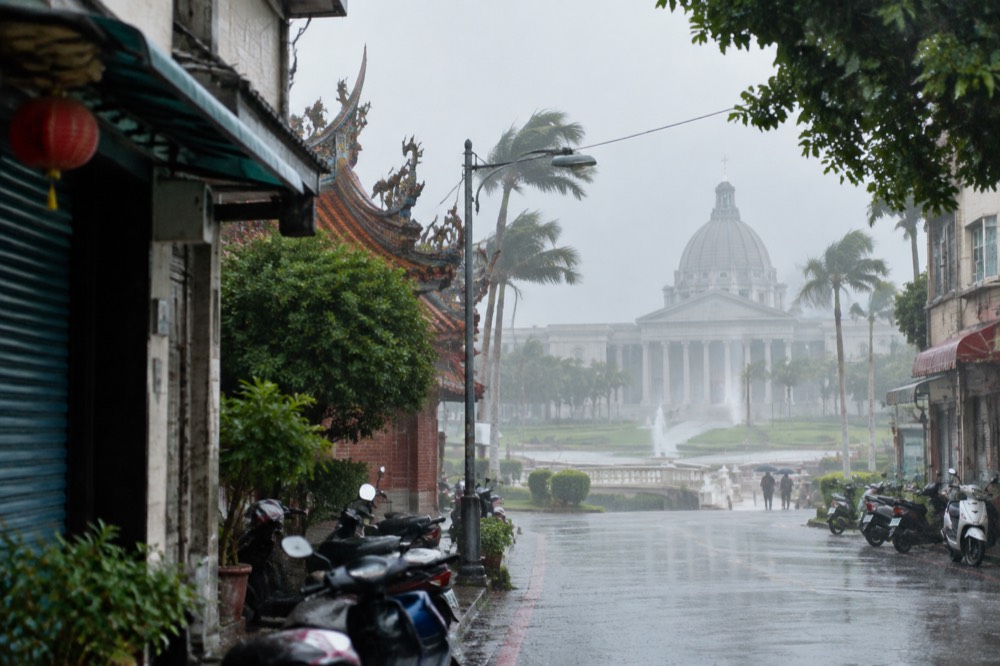 Palm trees bending in strong wind and rain outside a closed Tainan building