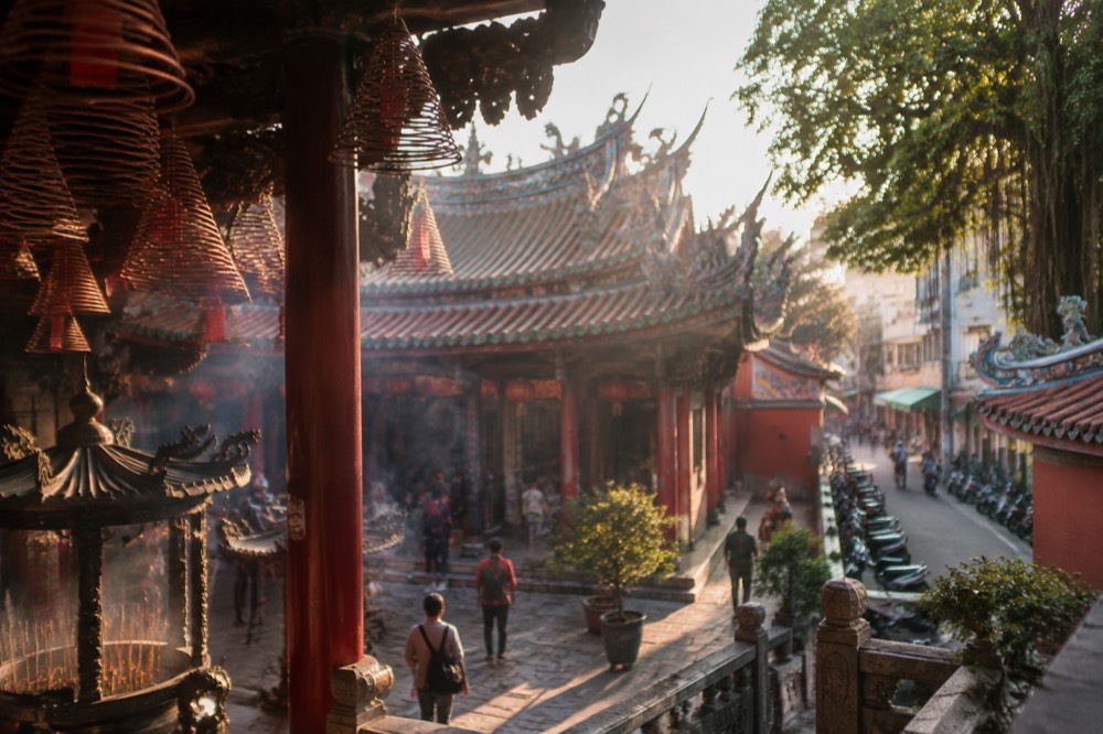A historic Tainan temple courtyard with red walls and a traditional tiled roof under a blue sky