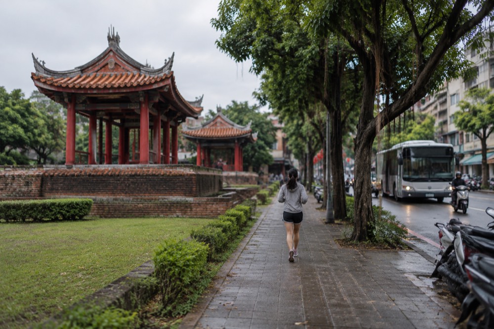 A Tainan city bus at a stop on a tree-lined street in the old city