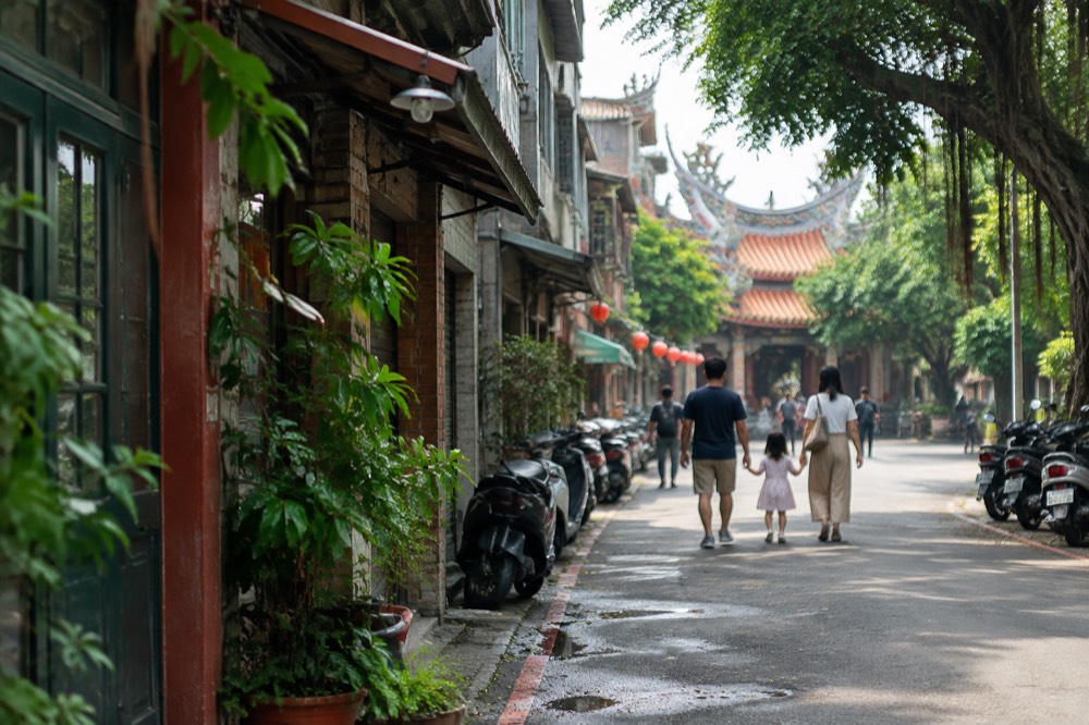 A family walking along a tree-lined old street in Tainan in warm afternoon light