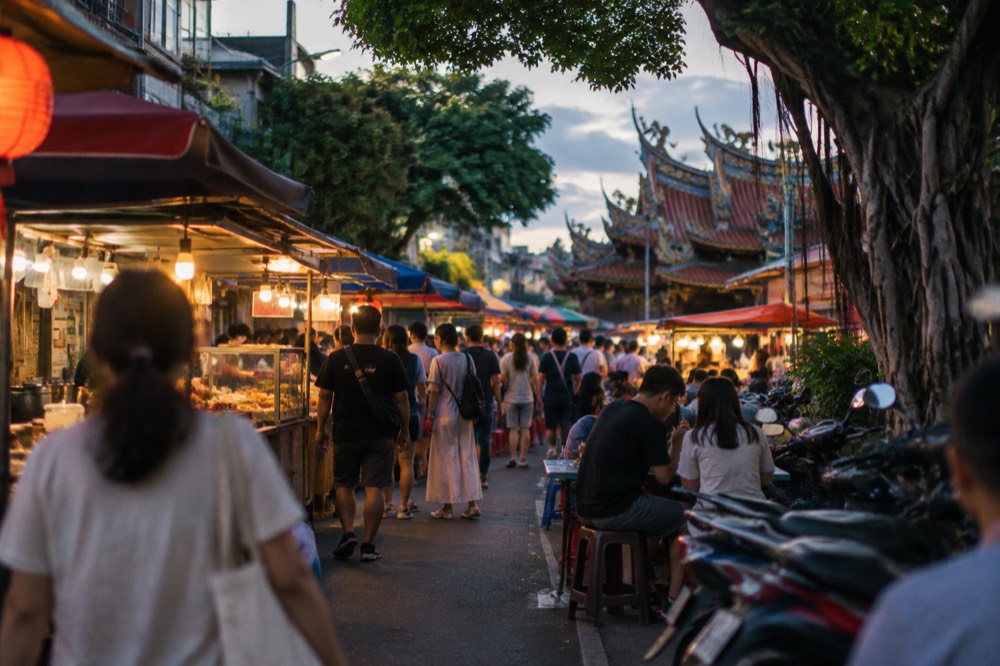 Families eating at lit food stalls in a crowded Tainan night market after dark